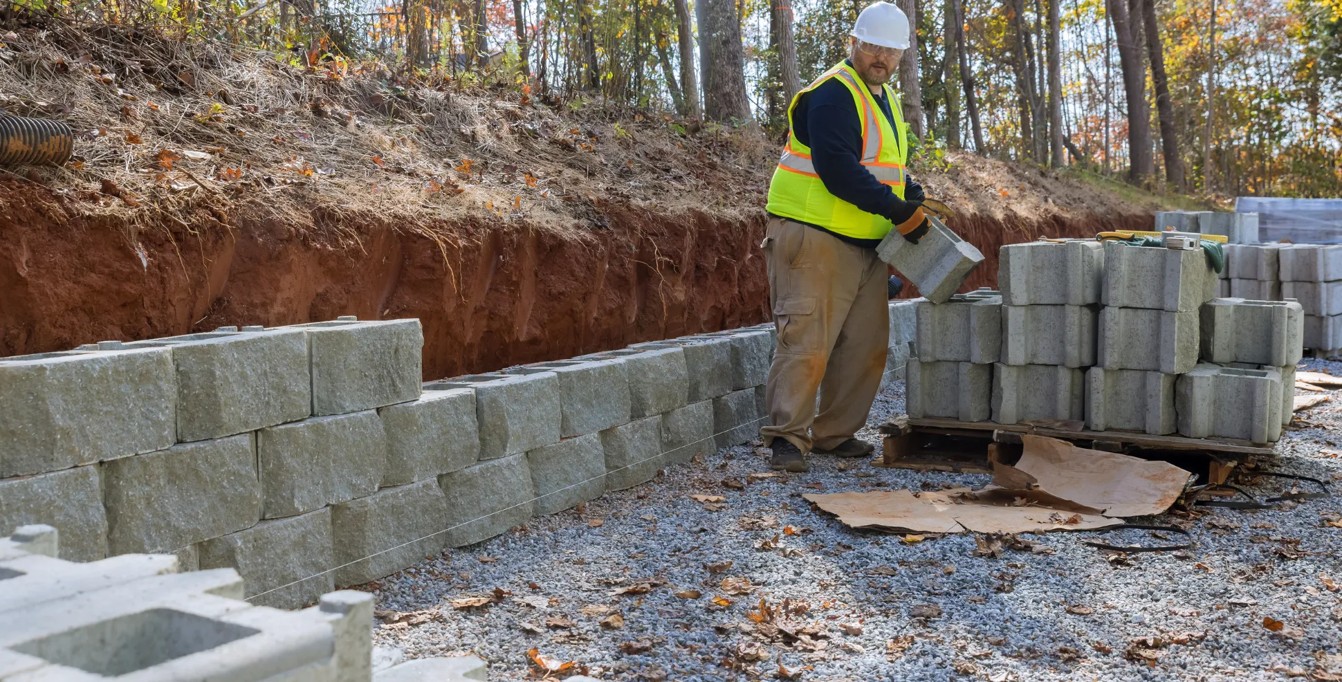 Contractor installing concrete retaining wall blocks during site preparation in Los Angeles