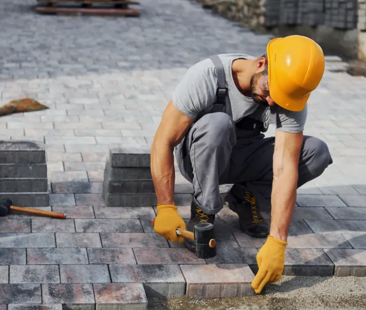 Concrete paver installation with worker leveling stones for a patio surface
