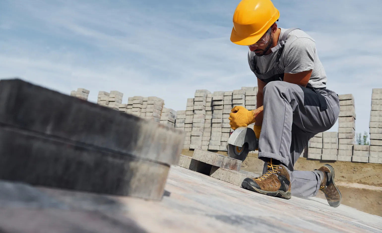 Worker cutting concrete pavers during hardscape installation on residential property